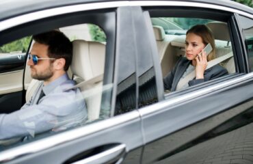 Businesswoman sitting on back seat in taxi car, talking on the phone.